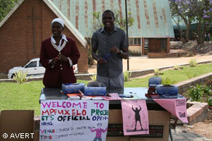 Two persons standing behind a display that's says Welcome to Mpfuxelelo project